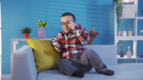 Disabled-dwarf-young-man-resting-on-sofa-at-home-and-looking-at-his-smartphone.